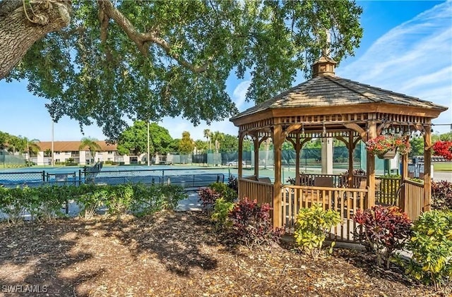 view of home's community with a tennis court, fence, and a gazebo