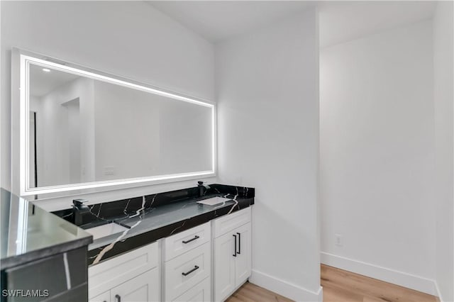 bathroom with double vanity, baseboards, and wood finished floors