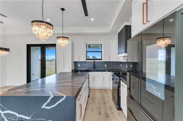 kitchen featuring dark countertops, black range with electric stovetop, decorative backsplash, an inviting chandelier, and a sink