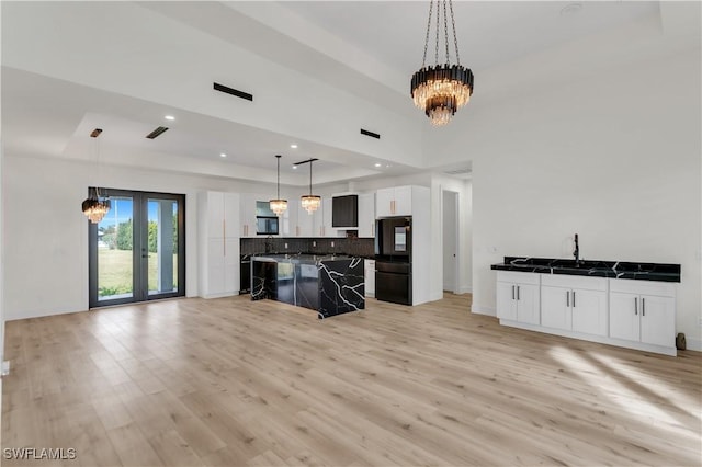 kitchen with freestanding refrigerator, light wood-style flooring, a tray ceiling, and an inviting chandelier