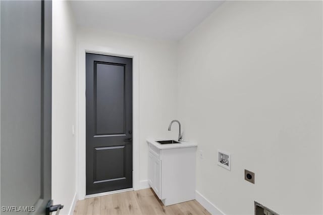 laundry room featuring baseboards, light wood-style flooring, hookup for an electric dryer, washer hookup, and a sink