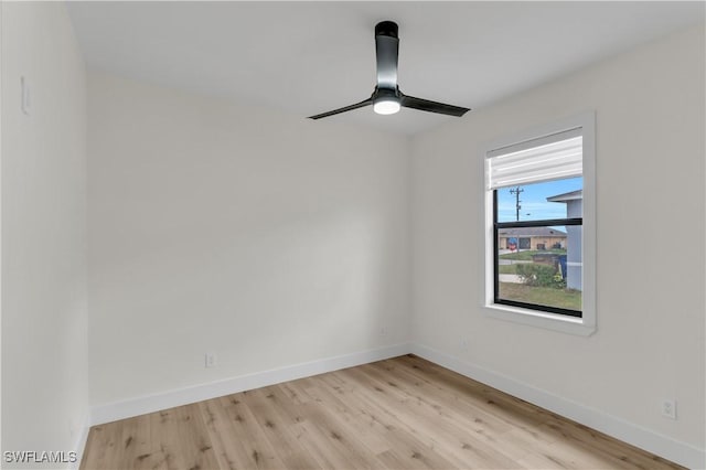 spare room featuring light wood-type flooring, ceiling fan, and baseboards