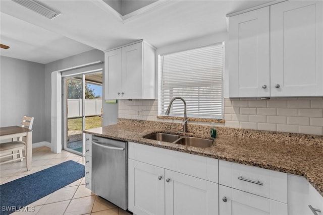 kitchen featuring a sink, dark stone counters, dishwasher, and light tile patterned floors