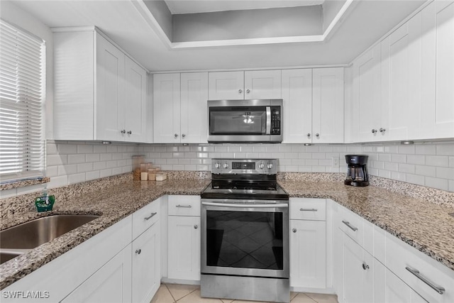 kitchen featuring stainless steel appliances, tasteful backsplash, and white cabinets