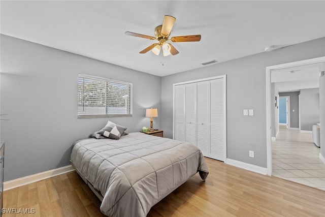 bedroom featuring light wood-type flooring, a closet, baseboards, and visible vents