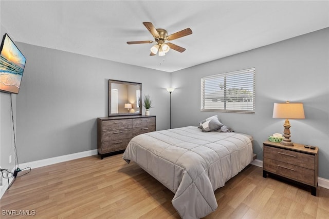 bedroom with light wood-style flooring, a ceiling fan, and baseboards