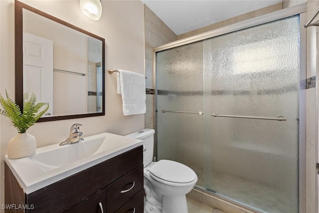 bathroom featuring vanity, toilet, a stall shower, and tile patterned flooring