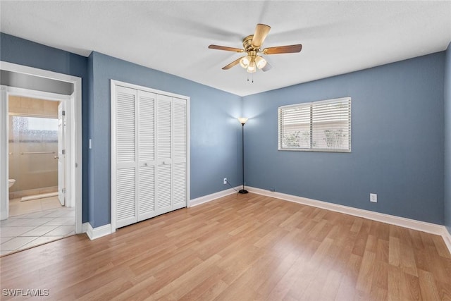 unfurnished bedroom featuring a closet, light wood-style flooring, baseboards, and ceiling fan