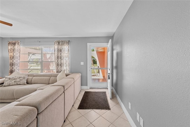 living room featuring light tile patterned floors, baseboards, and a textured wall