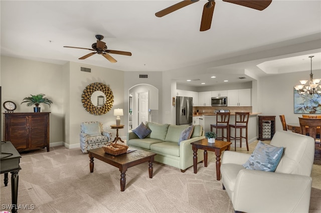 living room with arched walkways, recessed lighting, light colored carpet, visible vents, and baseboards