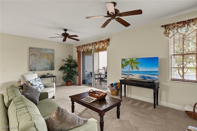 living area with baseboards, a ceiling fan, and light colored carpet