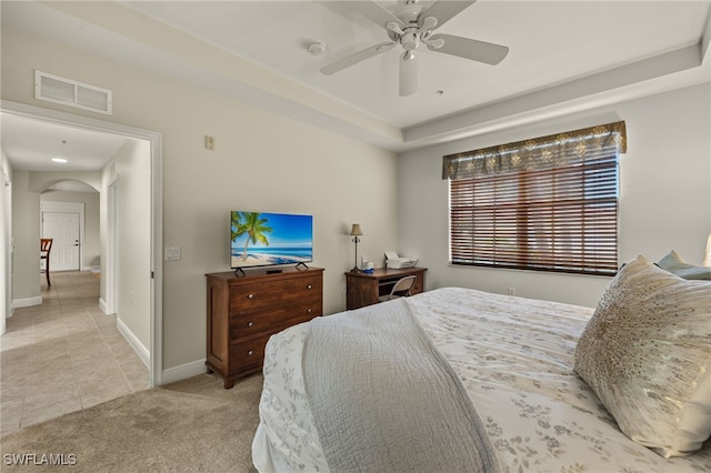 bedroom with baseboards, visible vents, arched walkways, light colored carpet, and ceiling fan