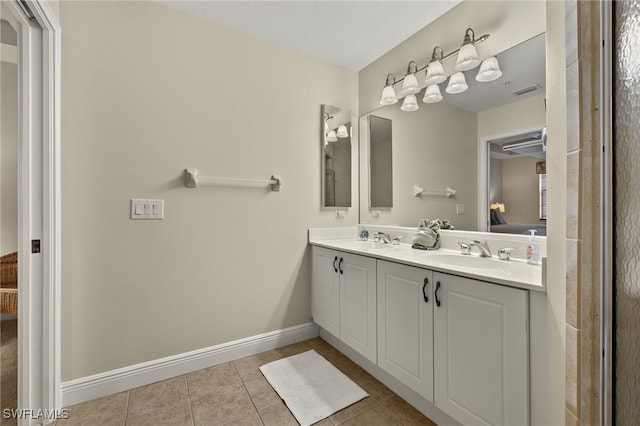 full bath with double vanity, ensuite bathroom, a sink, tile patterned flooring, and baseboards