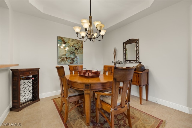 dining area featuring an inviting chandelier, baseboards, a tray ceiling, and light tile patterned flooring