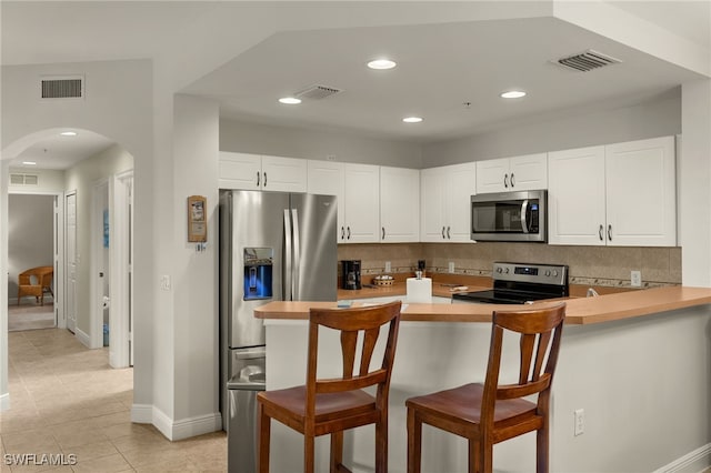 kitchen with stainless steel appliances, arched walkways, visible vents, and tasteful backsplash