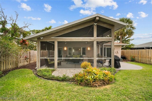 back of house featuring a sunroom, a fenced backyard, a lawn, and a patio