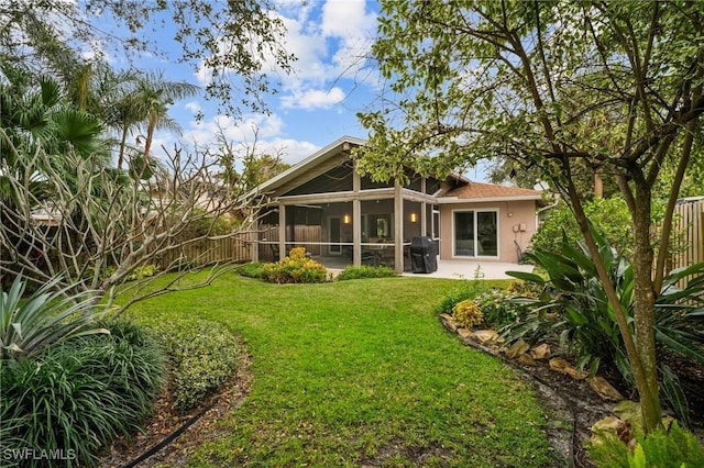 rear view of house featuring a lawn, a patio, a sunroom, fence private yard, and stucco siding