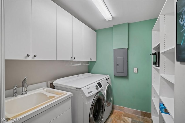 laundry room featuring cabinet space, stone finish floor, a sink, washer and dryer, and electric panel