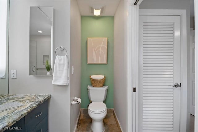 bathroom with toilet, baseboards, a closet, and vanity