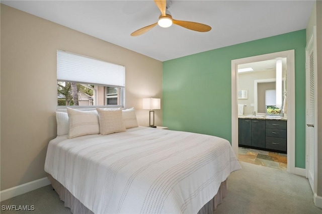 bedroom with light carpet, ceiling fan, baseboards, and connected bathroom