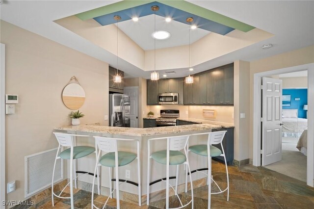 kitchen featuring a peninsula, a kitchen bar, visible vents, and stainless steel appliances