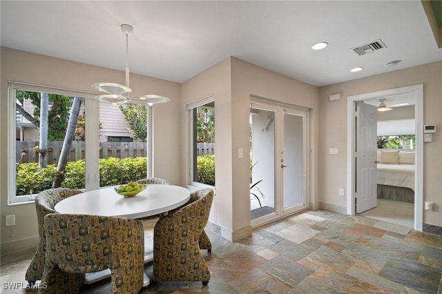 dining area with stone tile flooring, visible vents, baseboards, and an inviting chandelier