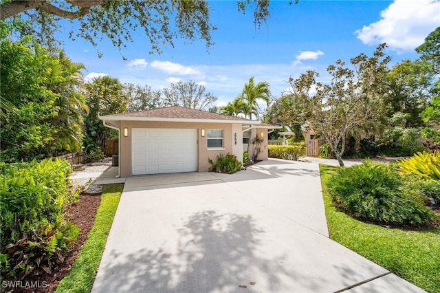 view of front facade with concrete driveway, an attached garage, fence, and stucco siding