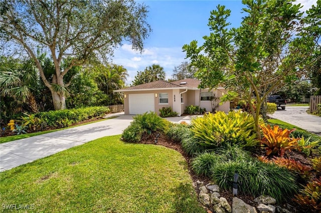 view of front facade with an attached garage, fence, concrete driveway, stucco siding, and a front lawn