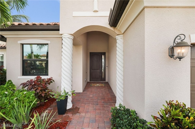 entrance to property featuring a tile roof and stucco siding