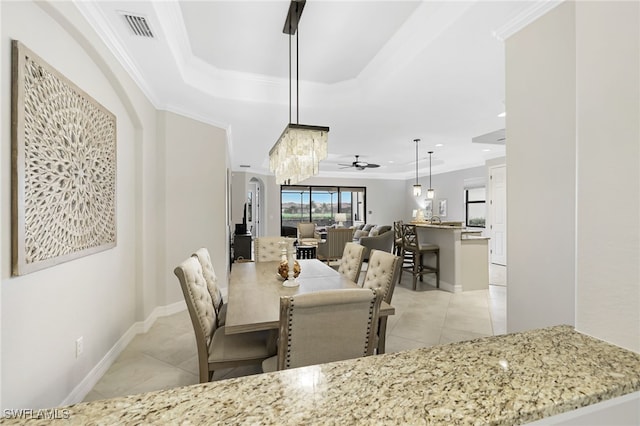 dining room with light tile patterned flooring, visible vents, a ceiling fan, ornamental molding, and a tray ceiling