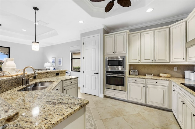 kitchen featuring a tray ceiling, decorative light fixtures, stainless steel appliances, ornamental molding, and a sink