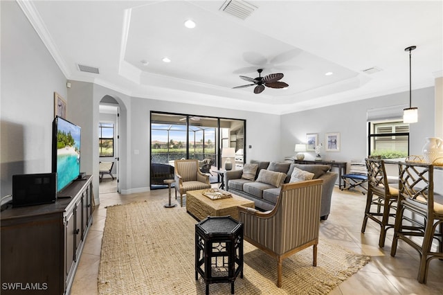 living area with crown molding, visible vents, and a tray ceiling