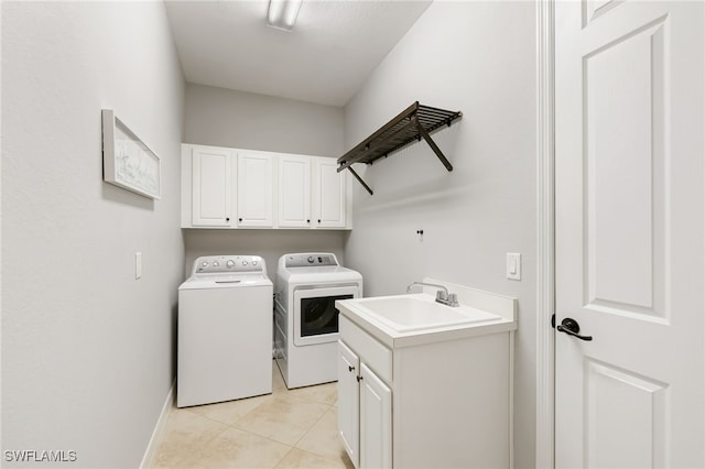 laundry room with washer and clothes dryer, light tile patterned floors, cabinet space, a sink, and baseboards