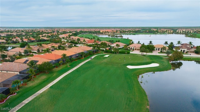 drone / aerial view featuring a water view, view of golf course, and a residential view