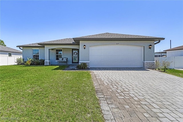 ranch-style house with decorative driveway, stucco siding, fence, a garage, and a front lawn