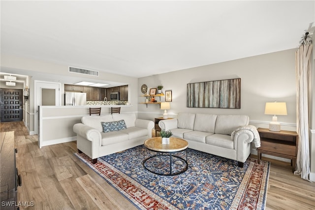 living area with light wood-type flooring and visible vents