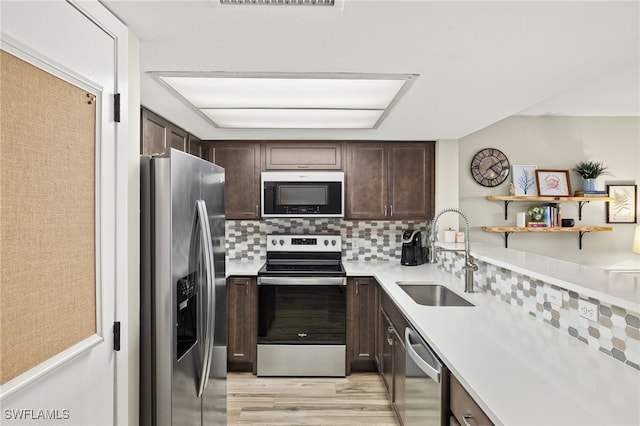 kitchen featuring dark brown cabinetry, stainless steel appliances, a sink, light countertops, and tasteful backsplash