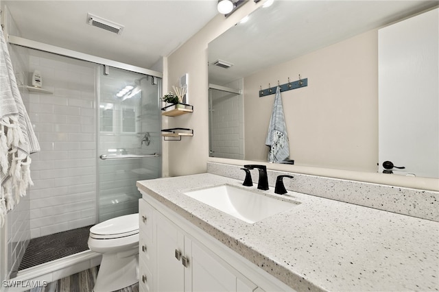 full bath featuring toilet, a stall shower, vanity, and visible vents