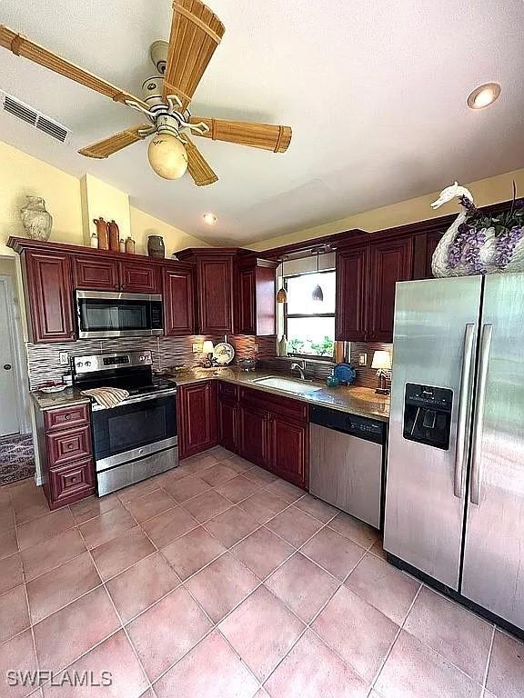 kitchen with lofted ceiling, a sink, visible vents, appliances with stainless steel finishes, and tasteful backsplash