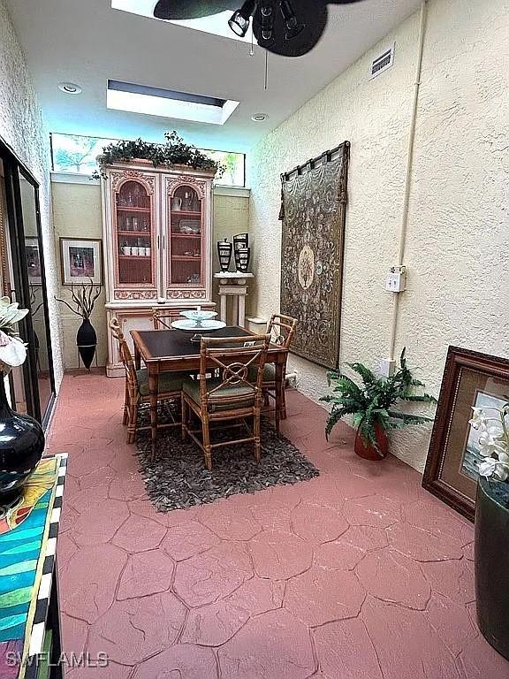 dining room with a textured wall, visible vents, and a ceiling fan