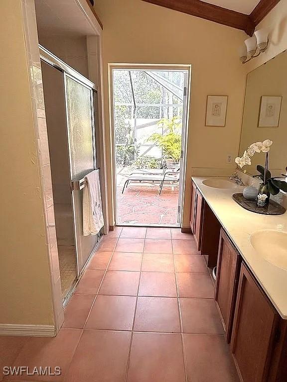 full bathroom featuring double vanity, a sink, a shower stall, tile patterned flooring, and baseboards