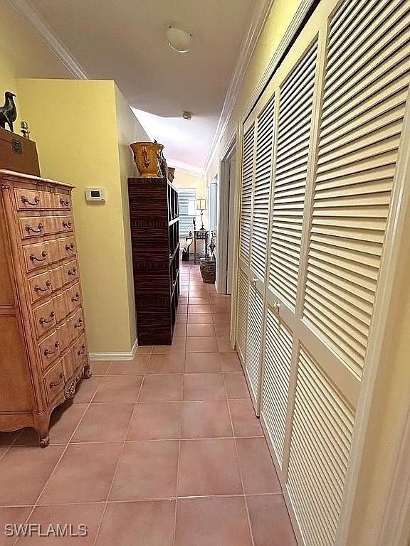 corridor with crown molding, baseboards, and light tile patterned floors