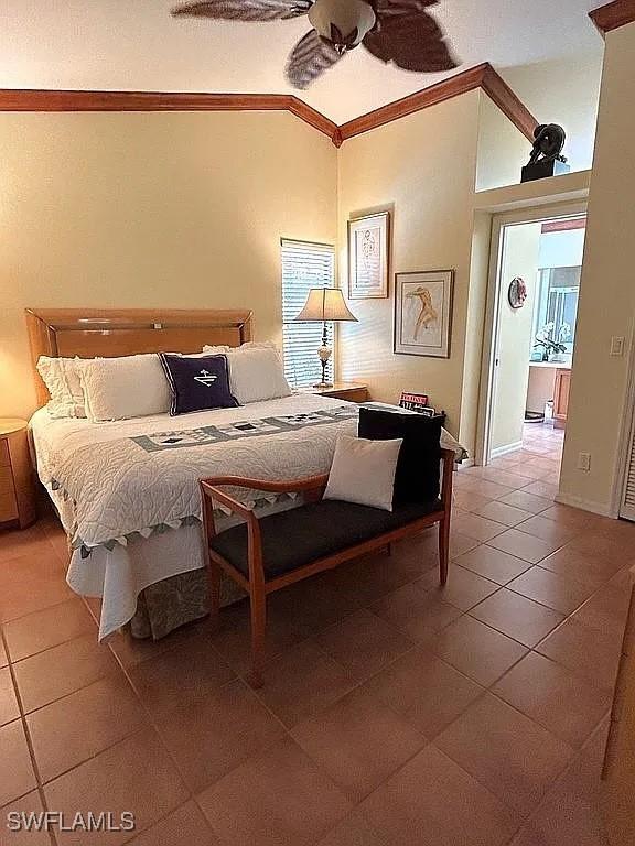 tiled bedroom featuring lofted ceiling, ceiling fan, ornamental molding, and baseboards