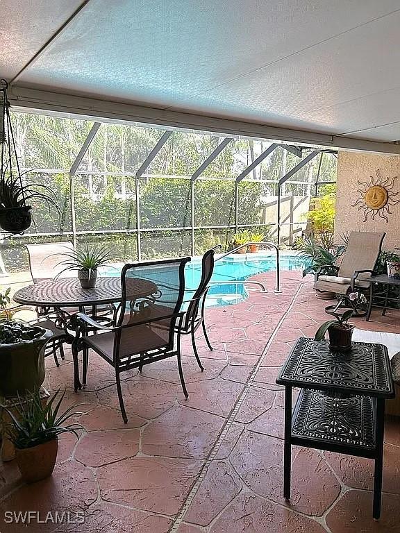 view of patio / terrace with glass enclosure and an outdoor pool