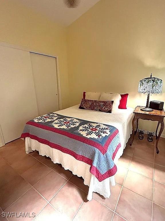 bedroom with lofted ceiling, a closet, and light tile patterned flooring