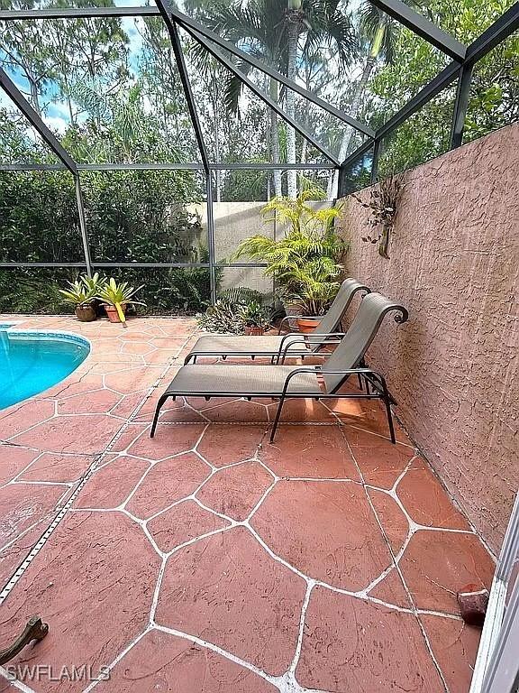 view of patio with glass enclosure and an outdoor pool