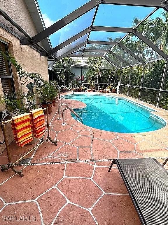 pool with a patio area and glass enclosure