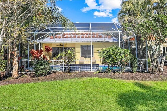 back of house with a lanai, a yard, an outdoor pool, and stucco siding