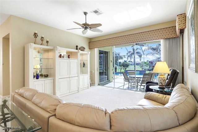 living room featuring light carpet, a sunroom, visible vents, and a ceiling fan