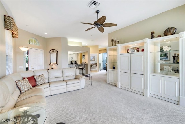 living room featuring a ceiling fan, visible vents, and light colored carpet